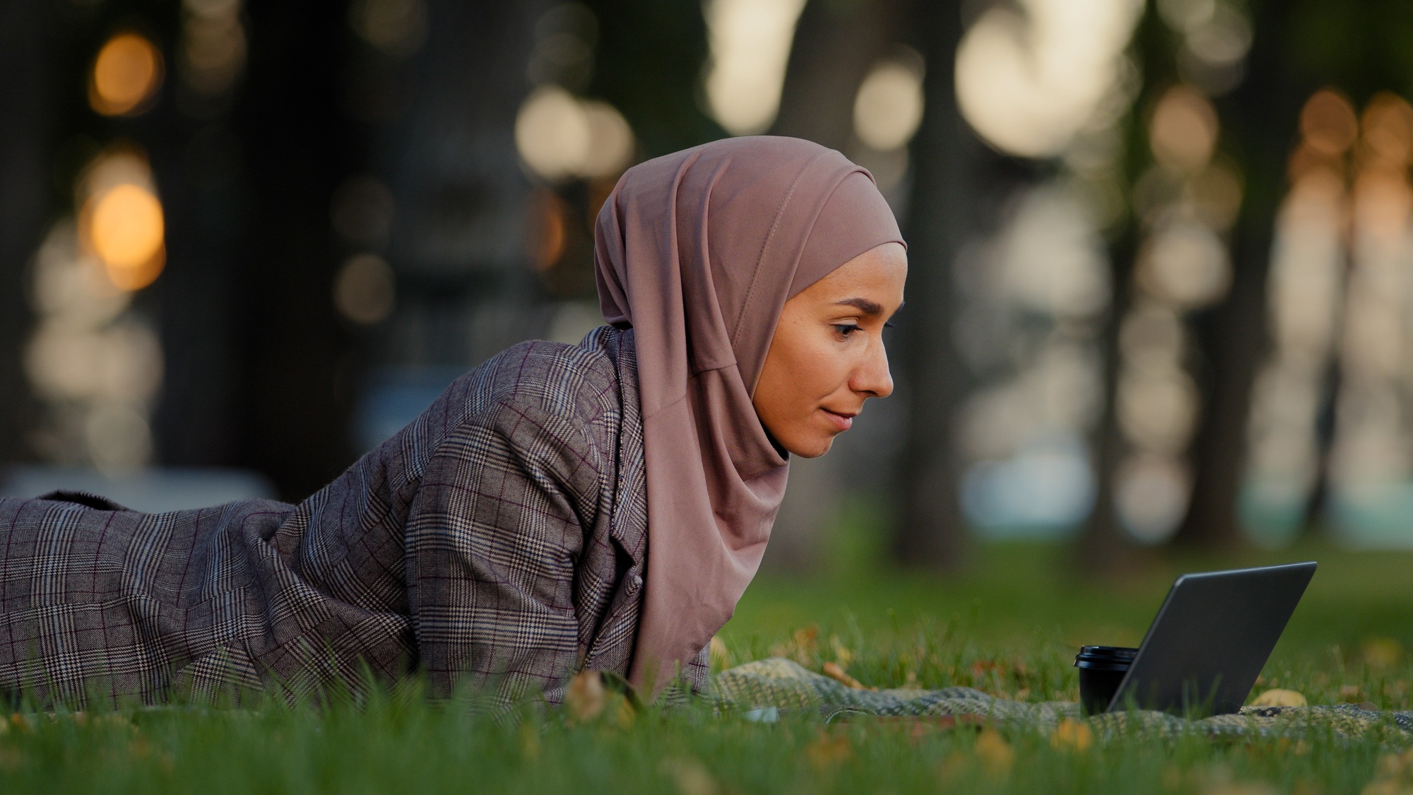 Friendly islamic business woman muslim girl in hijab lying grass lawn in park outdoors female