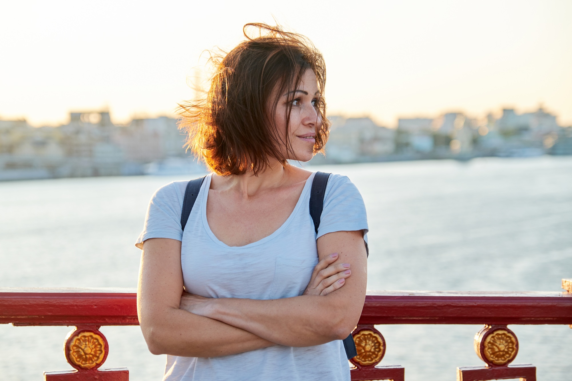 Outdoor portrait of mature beautiful happy woman with arms crossed
